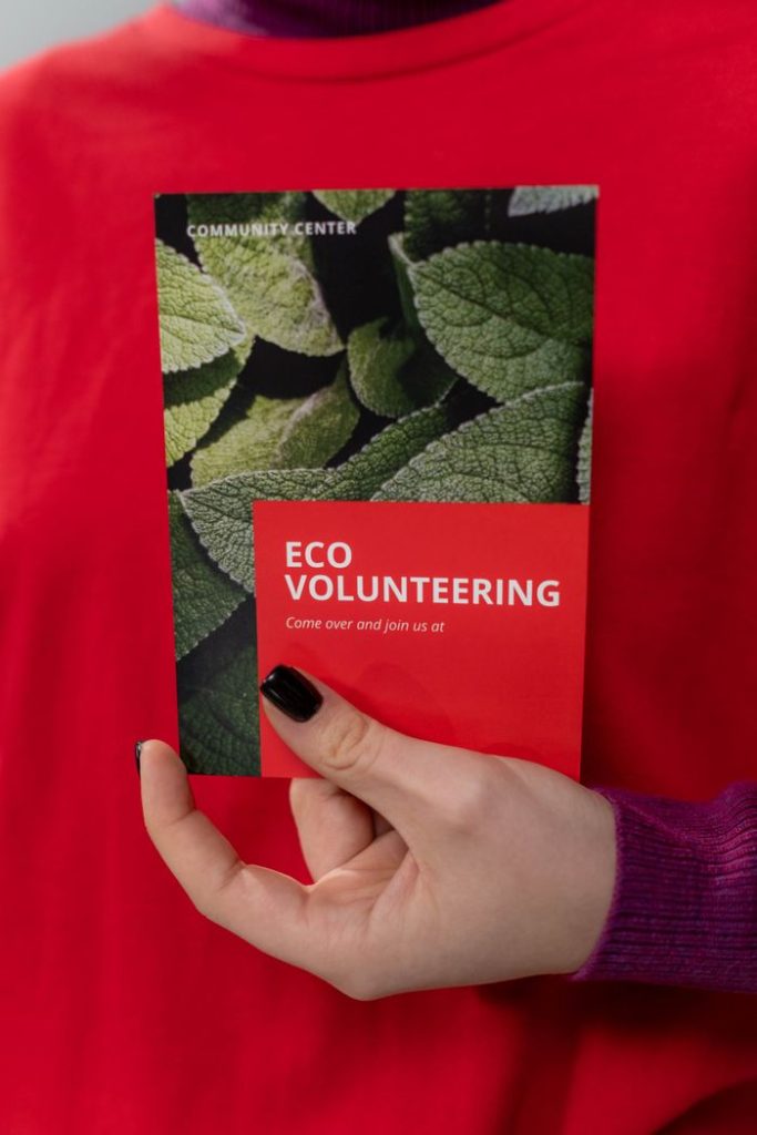 Close-up of a volunteer holding an eco volunteering brochure with nature design.